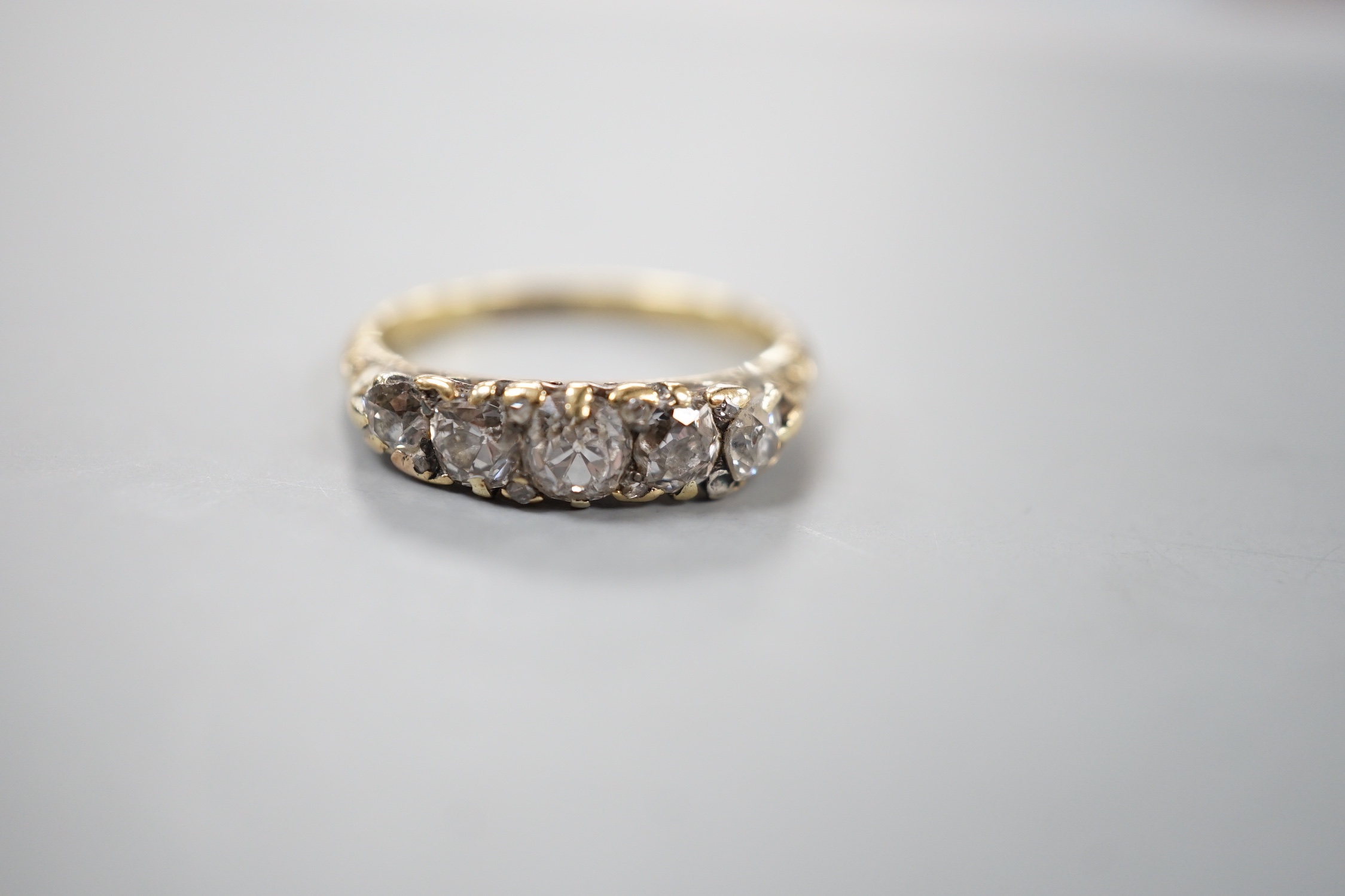 An 18ct and graduated five stone diamond set half hoop ring, size M, gross weight 3.5 grams.